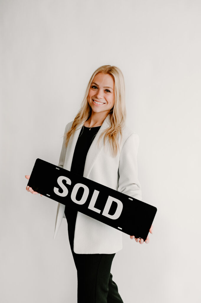 Realtor Madria Kuberra holding a "SOLD" sign.
